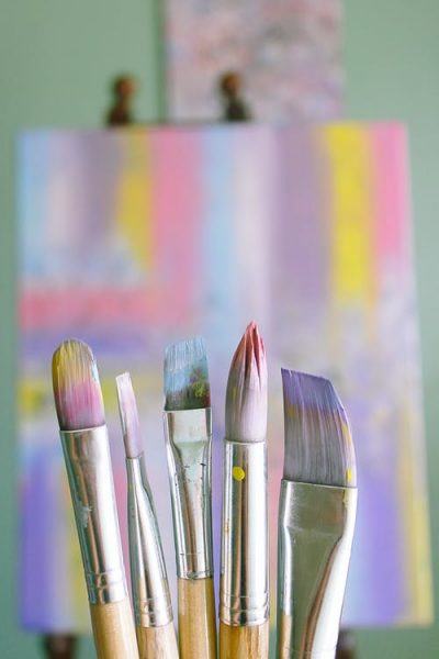 Pastel coloured paintbrushes in front of a canvas