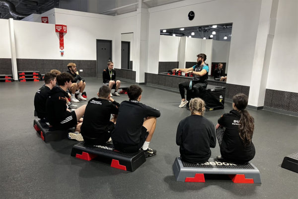 Students listening to their lecturer in the gym
